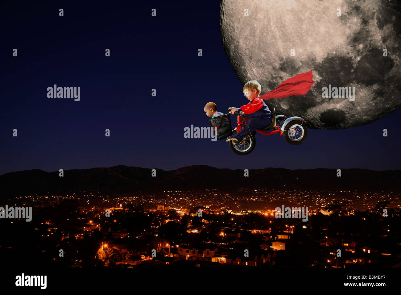 Un composite d'un petit garçon et de sa sœur volant par la lune sur son tricycle. Banque D'Images