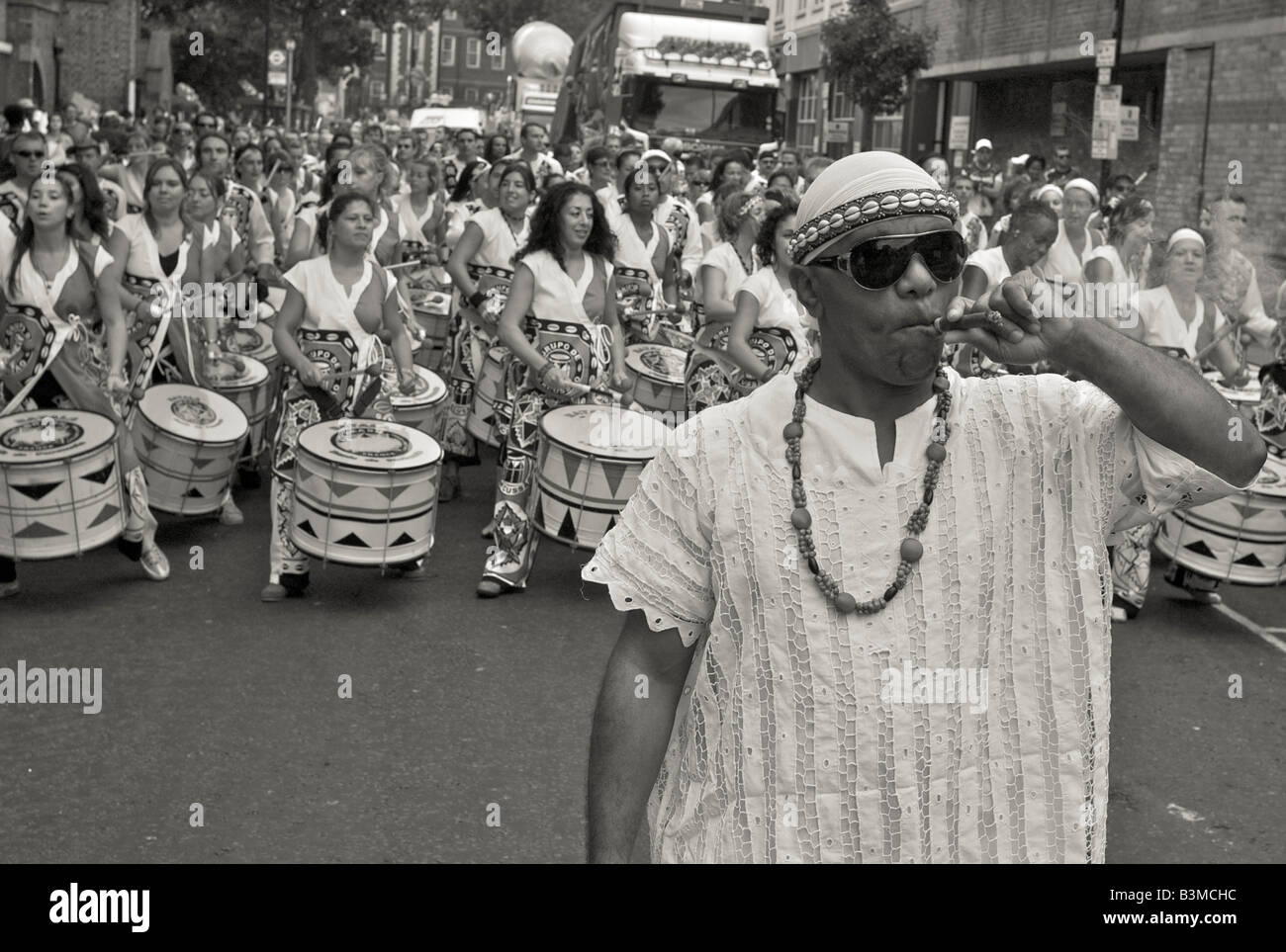 Arnival Notting Hill London 2008 Groupe de musique de samba avec leur chef en face de fumer un cigare Banque D'Images Arnival Notting Hill London 2008 Groupe de musique de samba avec leur chef en face de fumer un cigare Banque D'Images