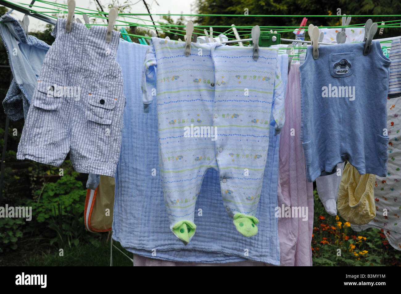Une sélection de vêtements de bébé de remettre sur un séchoir rotatif dans un jardin. Banque D'Images