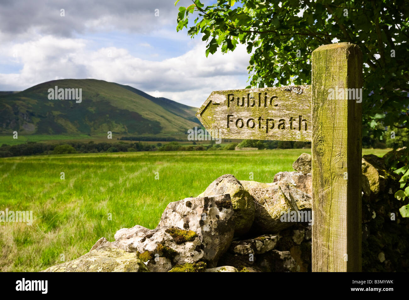 Panneau en bois sentier public signe et muret de pierres sèches qui donne sur le Lac de montagne du district de Cumbria, Angleterre, Royaume-Uni Banque D'Images