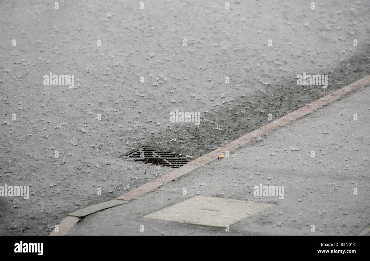 L'eau de pluie qui s'écoule dans un tuyau d'évacuation sur le côté d'une route à Redditch UK Worcestershire pendant un orage d'été Banque D'Images