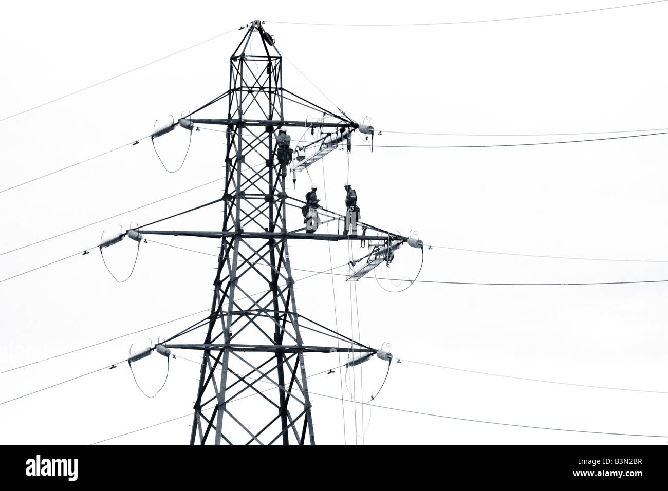 Les hommes travaillant sur un pylône elecricity Banque D'Images