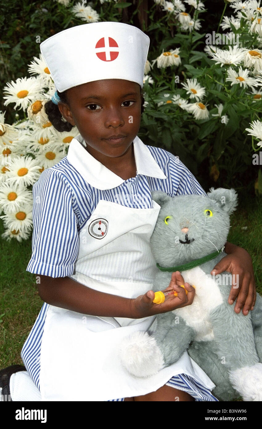 Petite fille noire dans un uniforme d'infirmière donnant son jouet cat une injection. Banque D'Images