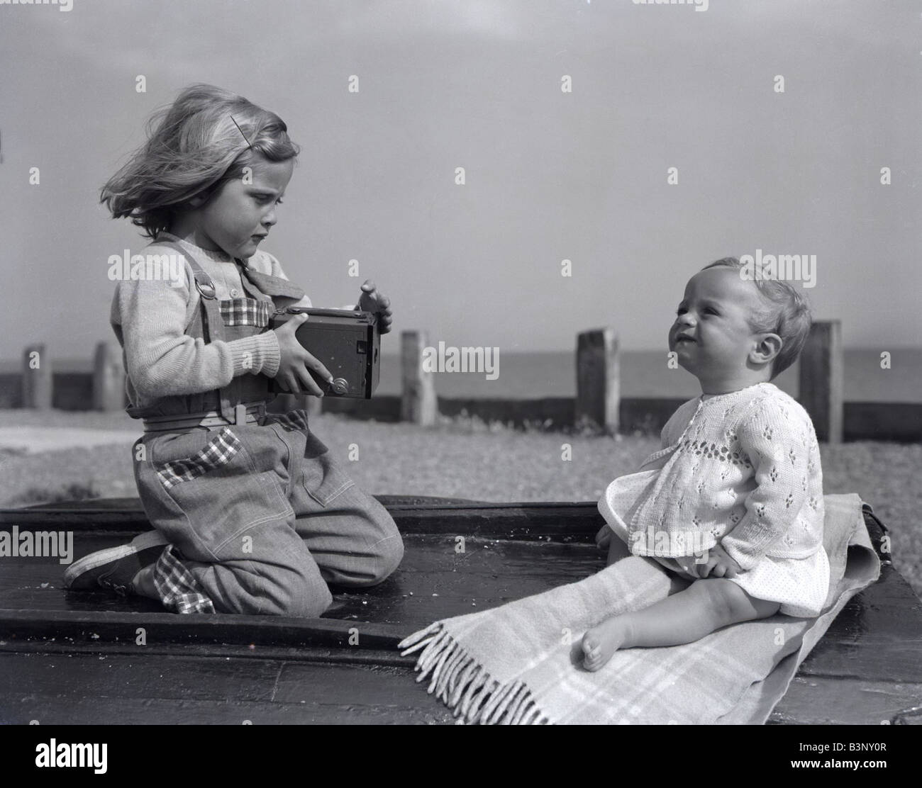 Une petite fille prend une photo de sa petite sœur sur la plage de  Brighton, tout en profitant du soleil de mai Mai 1954 Photo Stock - Alamy