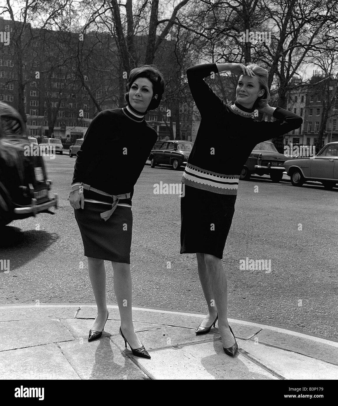 Pulls Fashion par Remploy 1964 Deux modèles féminins portant des robes similaires standing in street se présentant comme si à la recherche de quelqu'un Banque D'Images