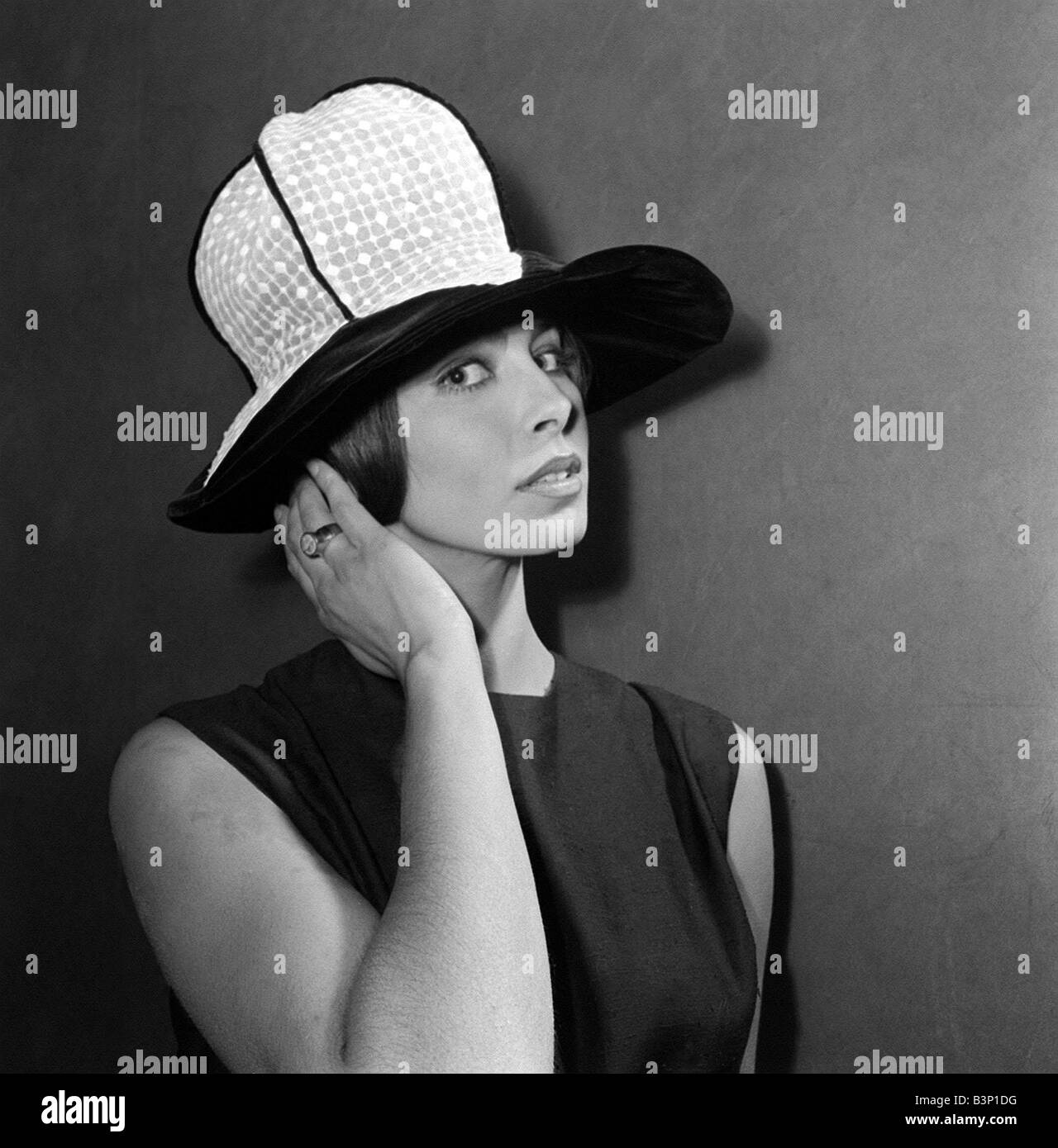 Chapeaux mode vêtements Janvier 1964 Un chapeau par l Haarup appelé brodé  blanc florentin et d'organdi bord en velours noir Sandra modèle Russell  tapotant ses cheveux Photo Stock - Alamy