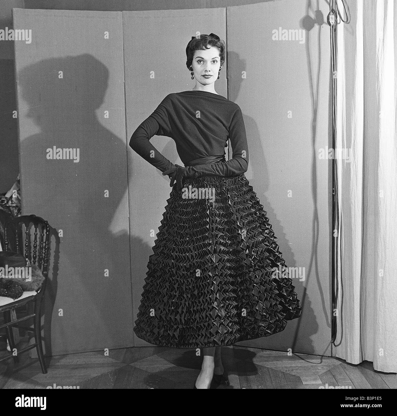 De Givenchy Fashion Show Novembre 1952 Model wearing black haut et golves avec une jupe ya ya texturé avec détail les mains jointes à sa hanche Banque D'Images