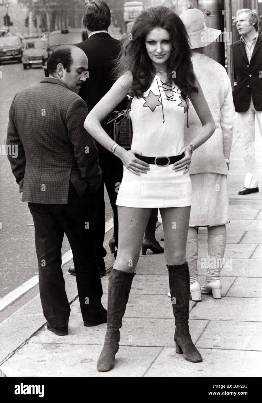 Modèle féminin Beulah Hughes portant une robe midi et bottes dans une rue de Londres comme un homme est d'obtenir une meilleure vue mai 1971 Vêtements femme womens mini jupe 1970 mirror La Diane 23 571 rowntree Banque D'Images
