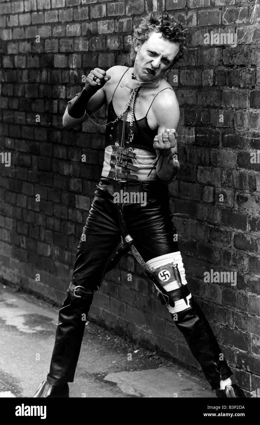 Punk Rocker de danser dans la rue par un mur portant un pantalon en cuir et top vest Banque D'Images