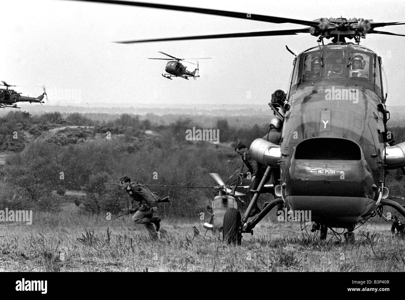 Drop d'équipement lourd répétition Avril 1967 Wessex Westland Helicopters soutien démontrer la circulation rapide d'hommes et de matériel pour une attaque par hélicoptère par deux compagnies du 3e bataillon du régiment de parachutistes vu ici près d'Aldershot en répétition pour une démonstration de l'utilisation de troupes aéroportées pour la Reine et le prince Philip les troupes britanniques les paras de l'armée les Diables Rouges un soldat s'exécute à partir de l'hélicoptère Banque D'Images
