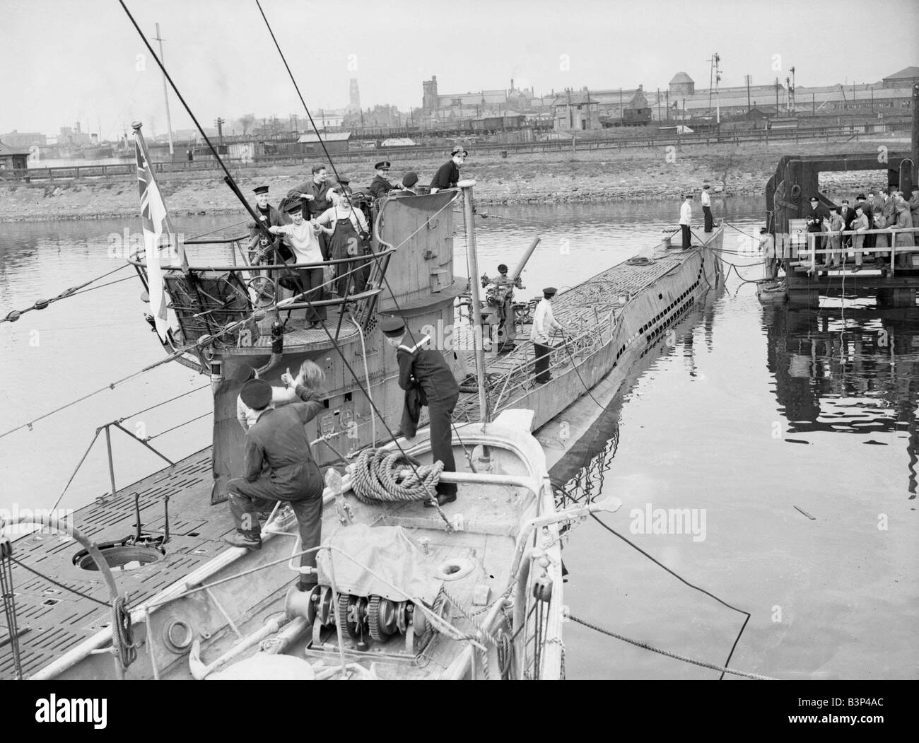 WW2 German U Sous-marin allemand U Premier Bateau Bateau pour être capturé intact est navigué dans le port avec un équipage de la Marine royale à bord du sous-marin est rencontré à quai avec des gestes bien fait bravo par d'autres marins Banque D'Images