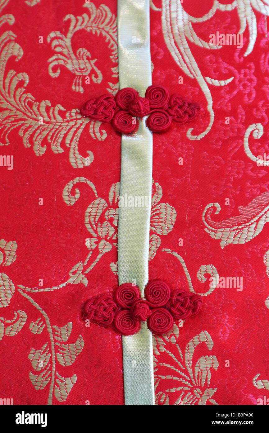 Boutons noués sur rouge et or robe en soie chinoise traditionnelle Banque D'Images
