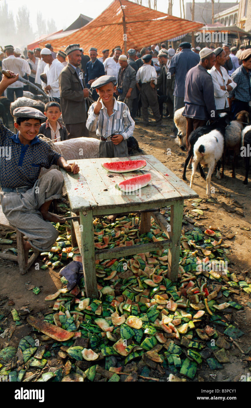 Chine, région autonome du Xinjiang Uigur, Kashgar. Les garçons Uigur vendre les pastèques de leur stand à Kashgar Marché du dimanche Banque D'Images