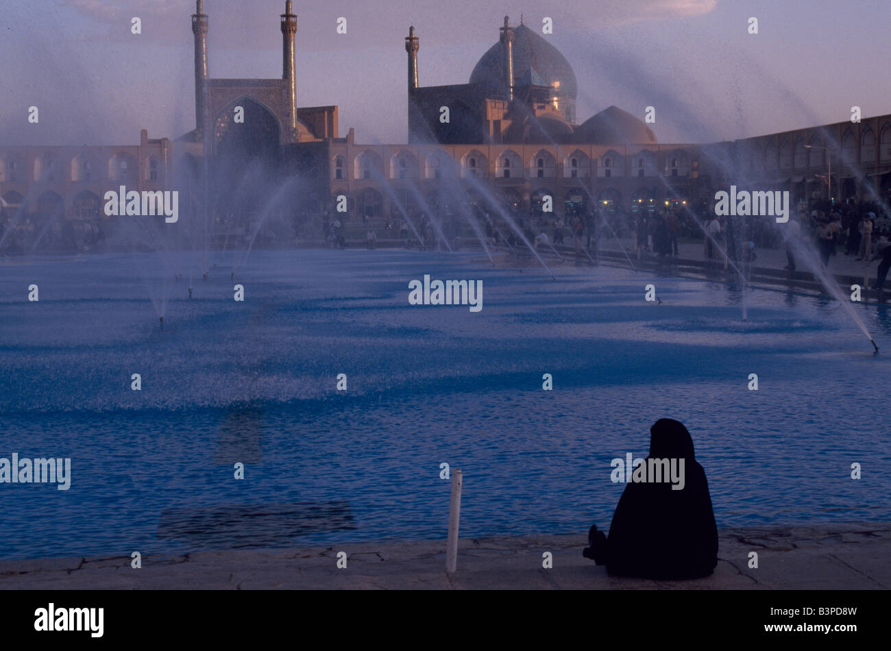 Iran, Ispahan. Une femme en costume traditionnel se trouve à à les fontaines de la place de l'Imam Khomeiny Banque D'Images