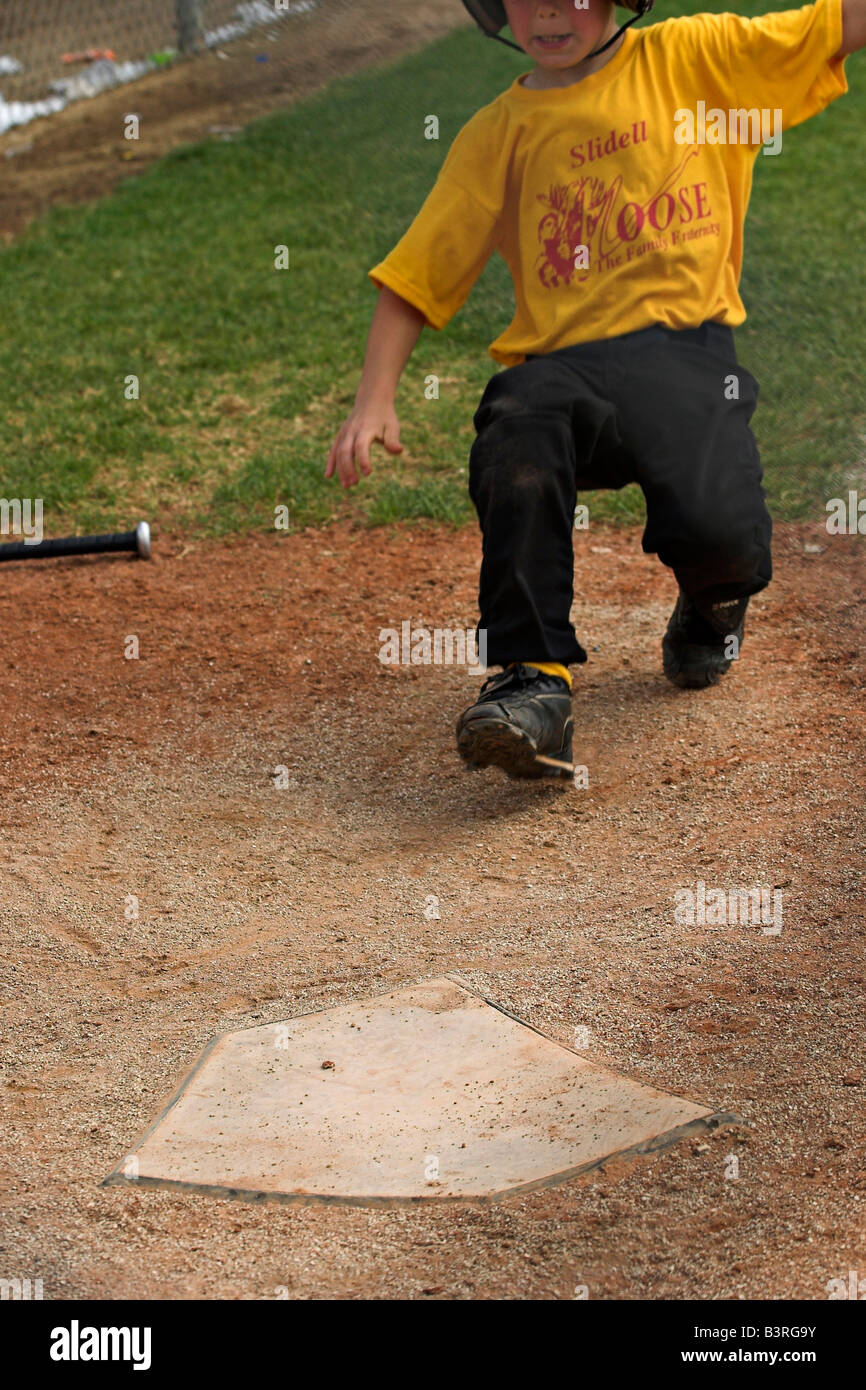 Une petite ligue de baseball se glisse dans la maison. Banque D'Images