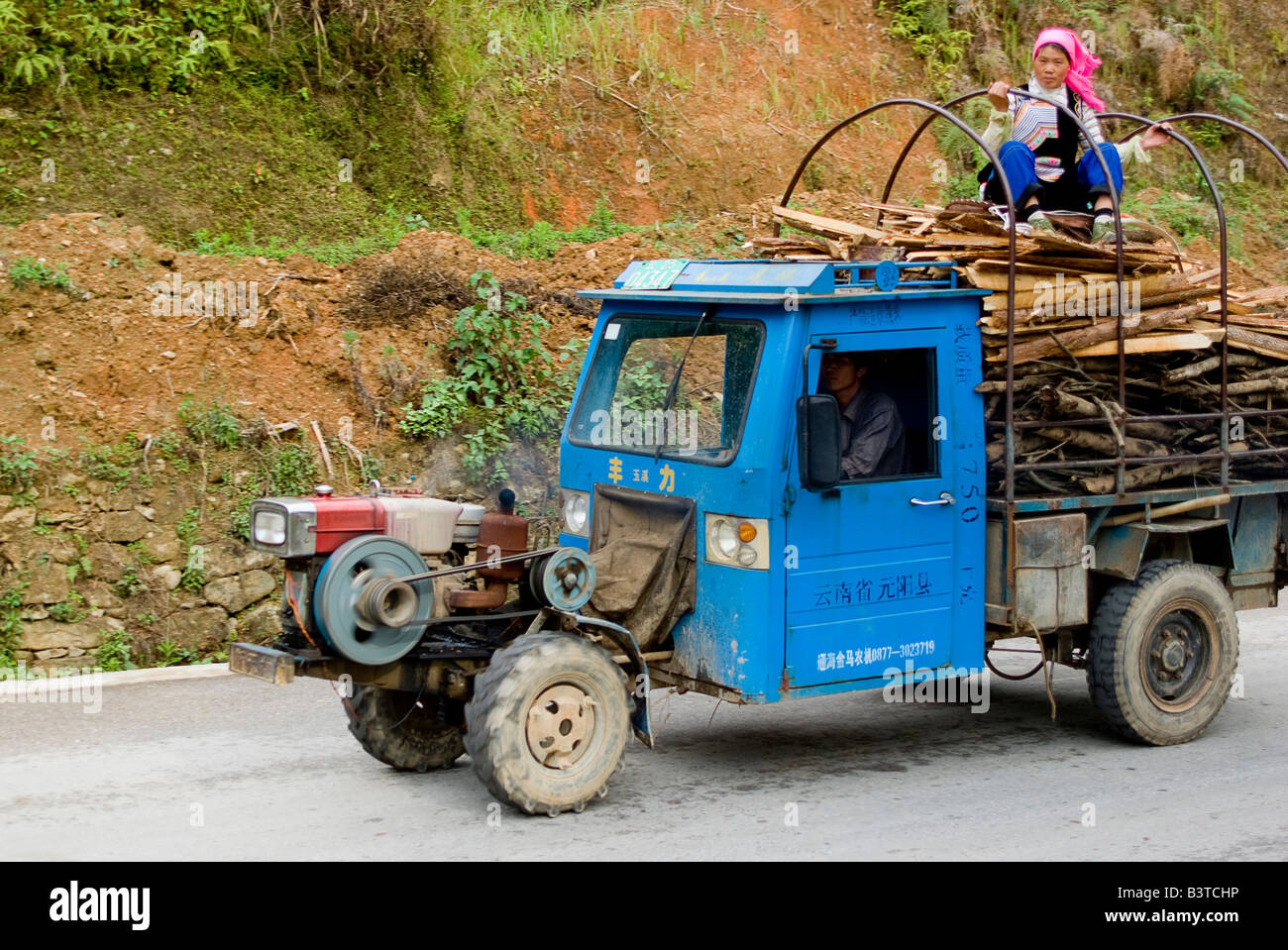L'Asie, Chine, Province du Yunnan, Yuanyang. Femme Yi rides au sommet d'un camion agricole. Banque D'Images