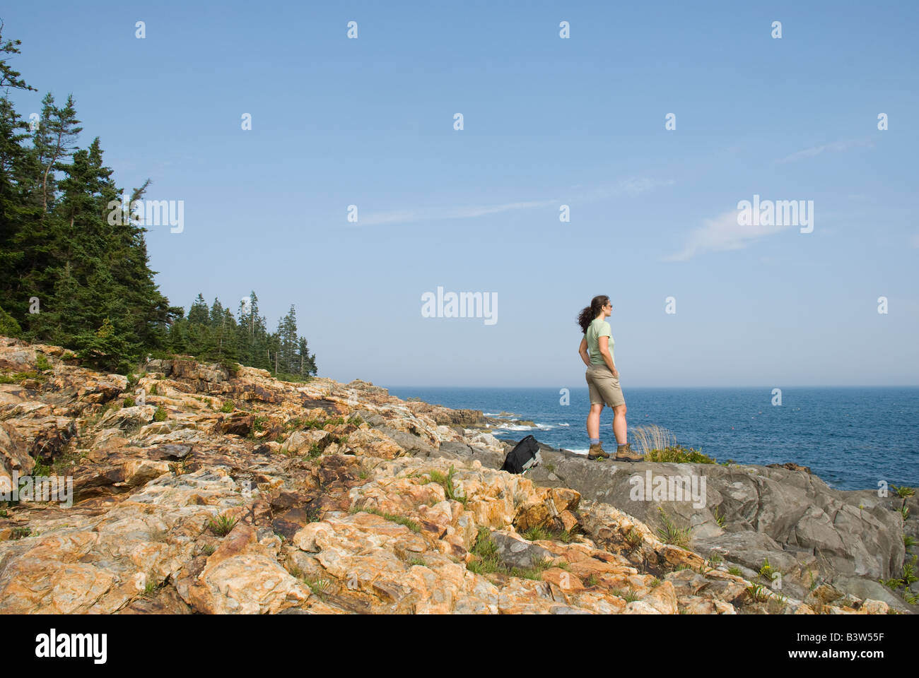 Une femme se tient sur la côte rocheuse du Maine Acadia National Park Banque D'Images