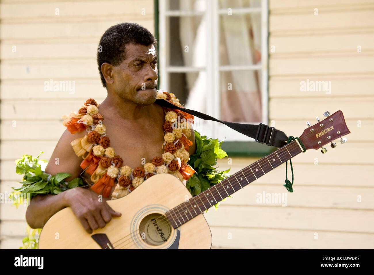 Océanie, Fidji, Viti Levu, Viseisei. Portrait d'un homme en costume autochtone tenant une guitare. Banque D'Images