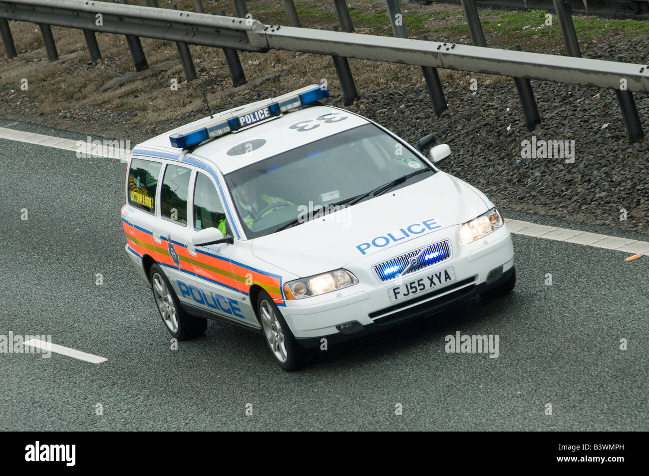 Volvo voiture de police accélérant le long d'une autoroute à un incident avec feux bleus clignotants et sirène Banque D'Images