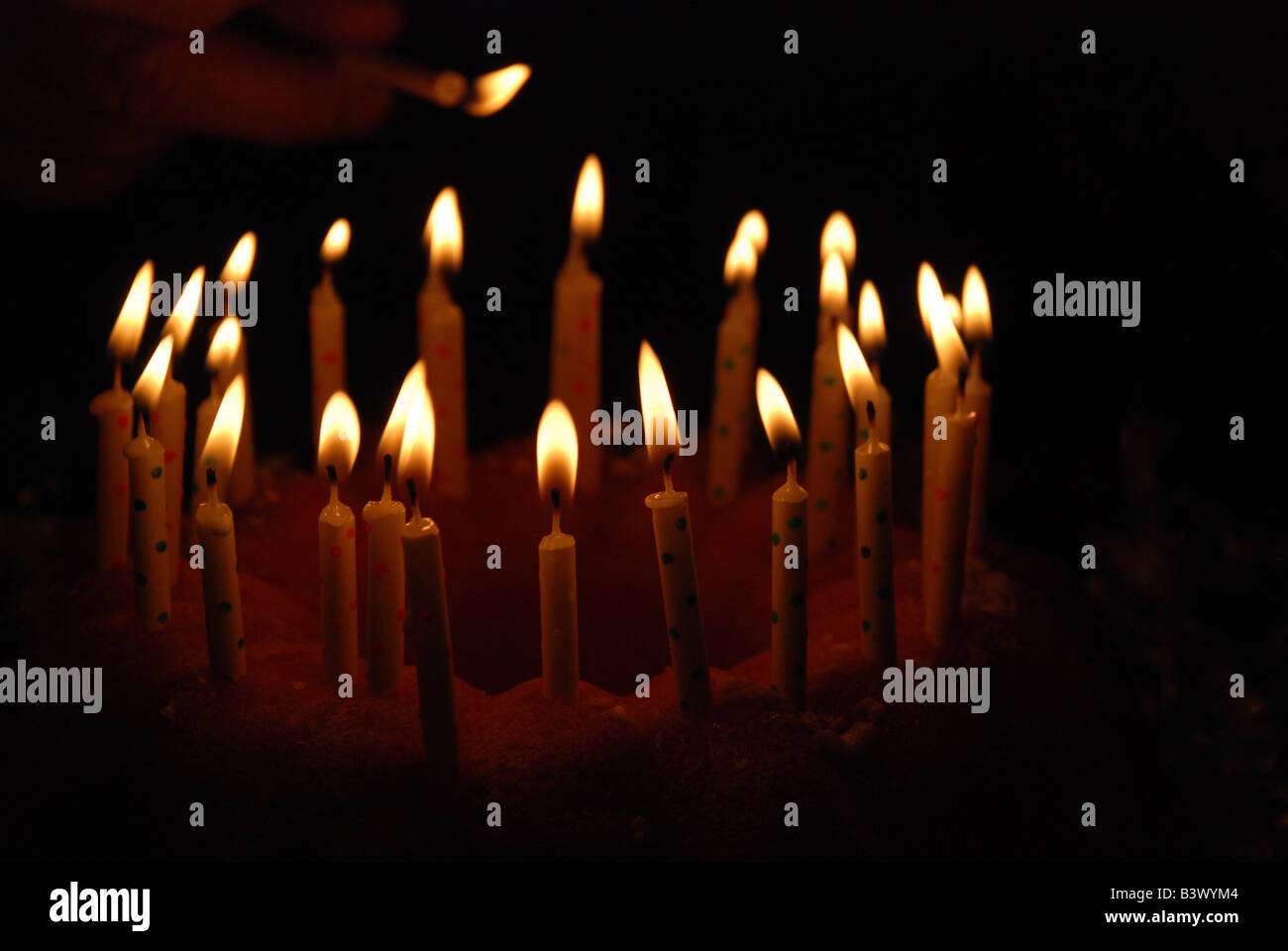 Un gâteau plein de bougies allumées sur un fond sombre. Banque D'Images
