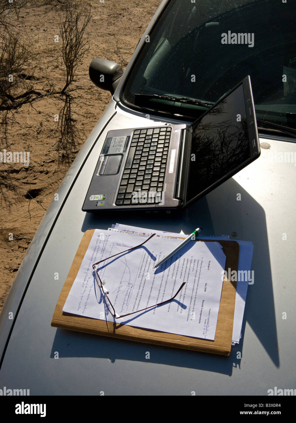 Ordinateur portable, lunettes, stylo et papier sur un moteur de voiture appuyez sur dans le domaine Banque D'Images