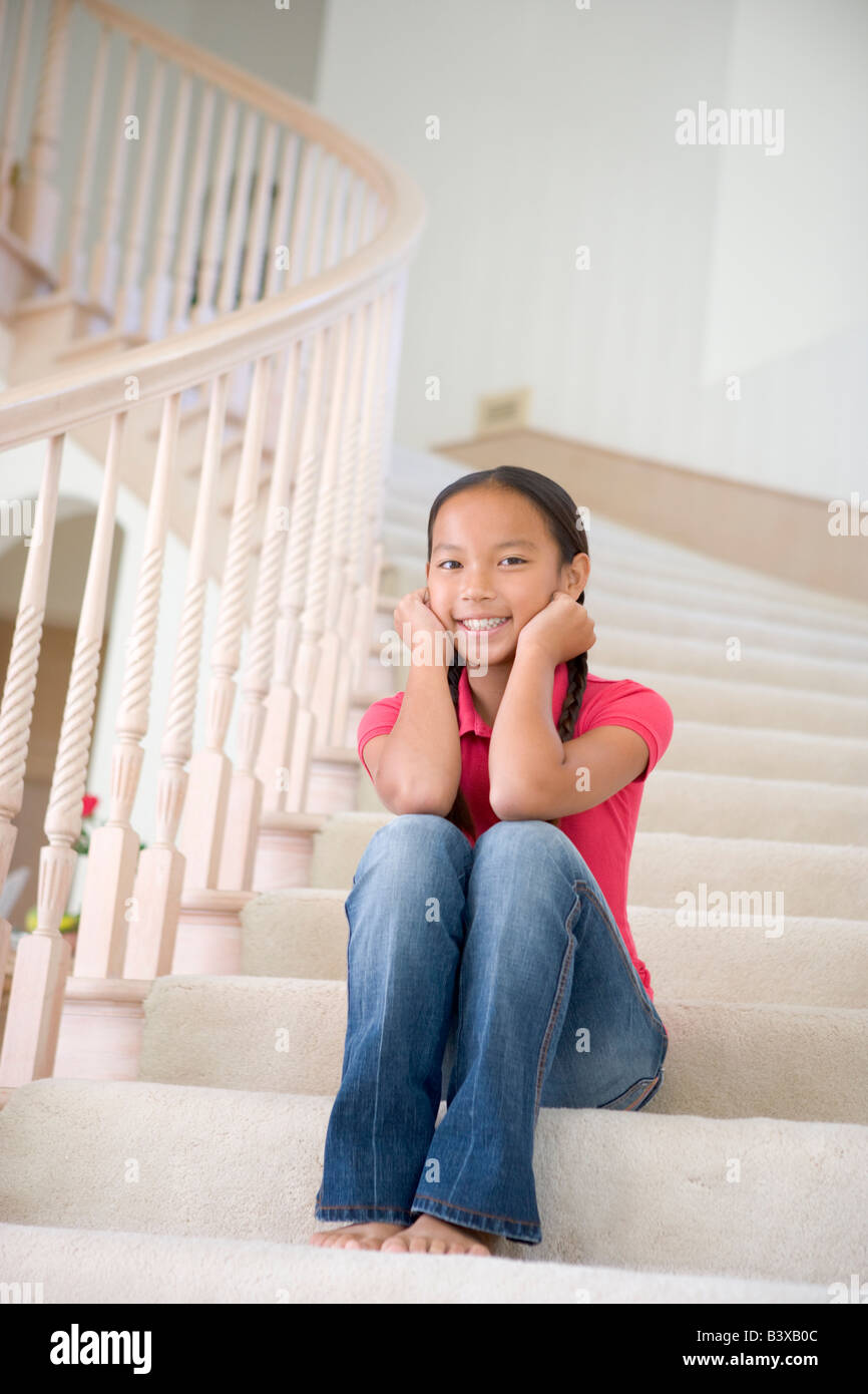 Jeune fille assise sur un escalier à la maison Banque D'Images
