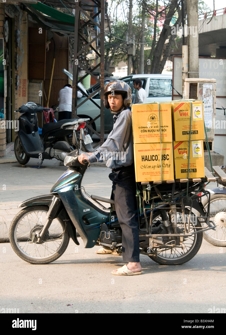 Un homme vietnamien transportant deux grandes boîtes à l'arrière de sa mobylette Banque D'Images