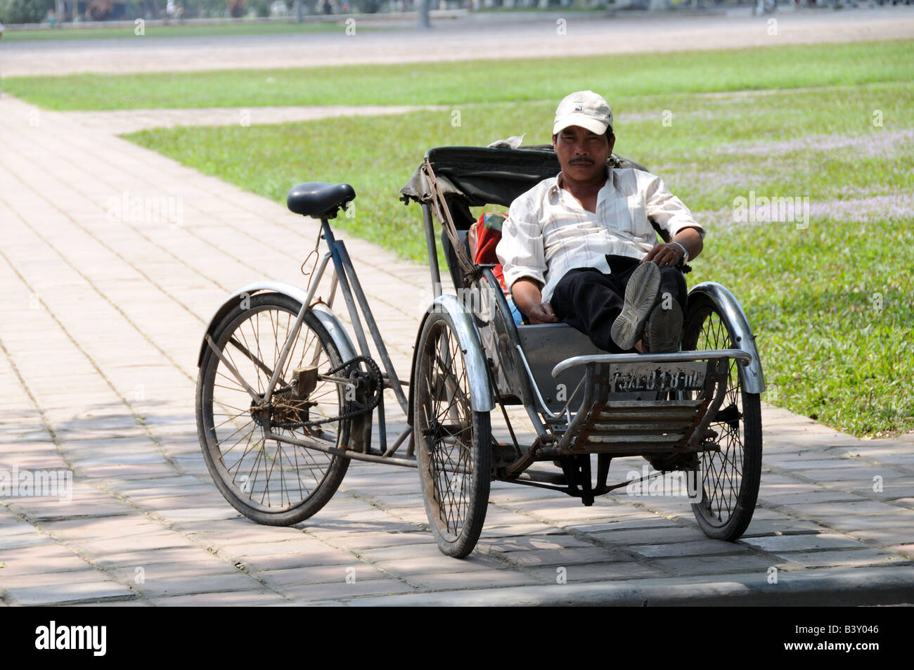 Homme assis vietnamiens dans son vélo-taxi ou en vélo-pousse les clients en attente de Ho Chi Minh City Vietnam Banque D'Images