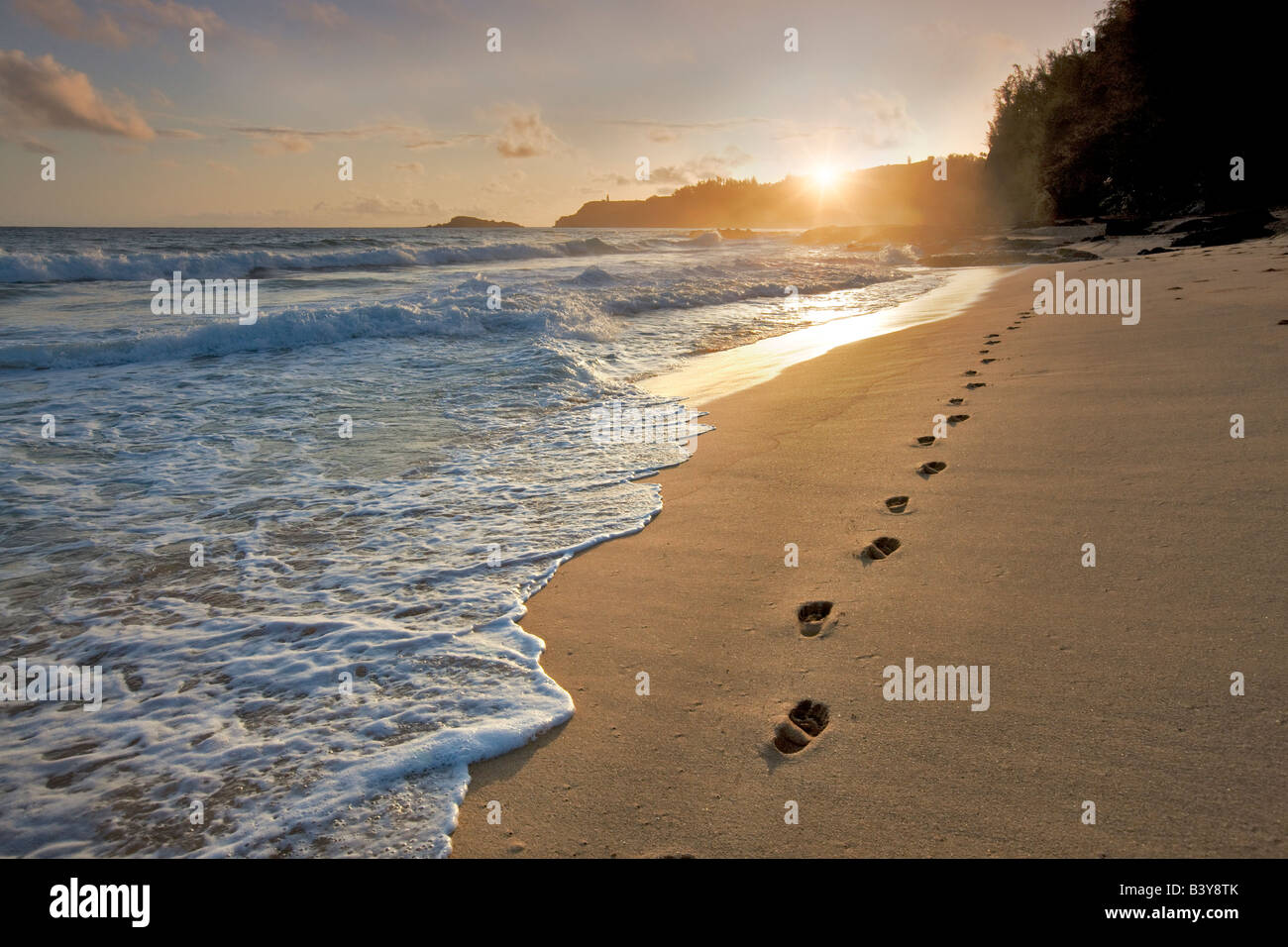 Lever de soleil à la plage secrète avec des empreintes dans le sable Kauai Hawaii Banque D'Images