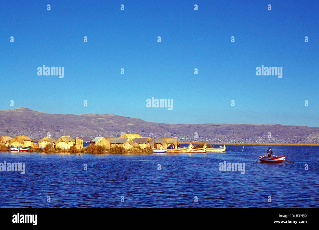 Le Pérou, Puno, un Indien lignes son bateau de l'un de l'Uros ou flottante sur le lac Titicaca, îles rouge Banque D'Images