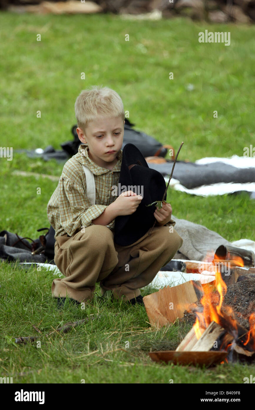 Un garçon assis près d'un feu de camp dans une guerre civile Reenactment Campement Banque D'Images