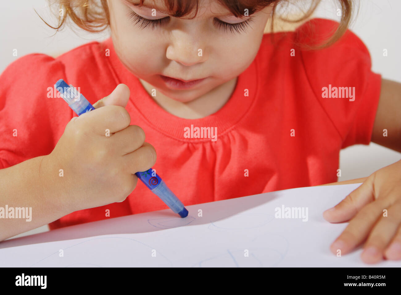 Deux ans d'un bébé fille est l'élaboration d'une holding maladroitement. crayon de couleur bleu Banque D'Images