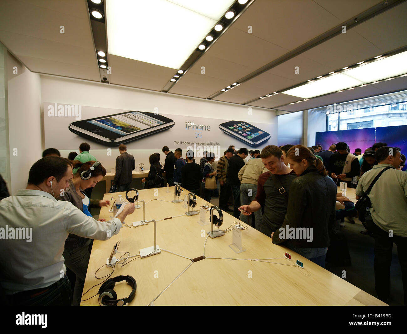 Les gens observant le nouvel iPhone 3G dans la partie très animée Apple Store de Regent Street London UK Banque D'Images