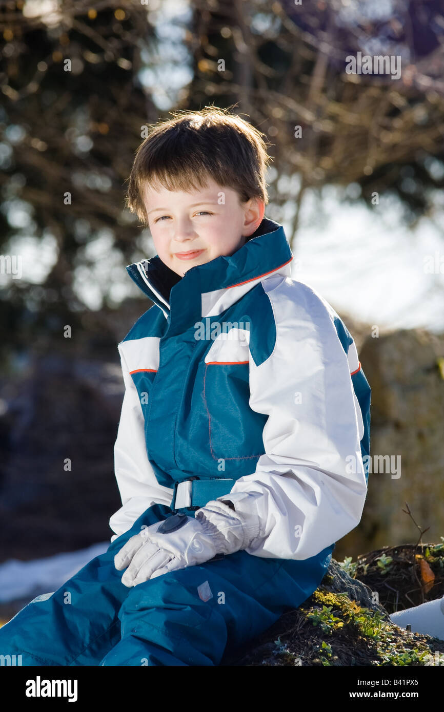 A smiling boy pose à l'extérieur en vêtements de ski et des gants. Portrait de trois-quarts. Banque D'Images