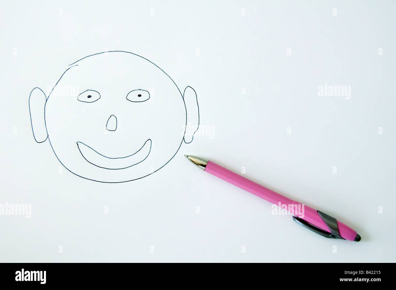 Visage souriant à côté de stylo à bille sur papier blanc rose Banque D'Images