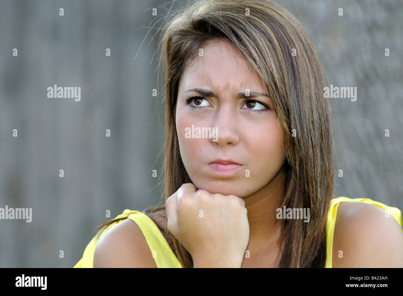 16 ans, jolie jeune fille de race blanche, cheveux bruns et yeux a une expression de colère sur son visage. Image conceptuelle. Banque D'Images