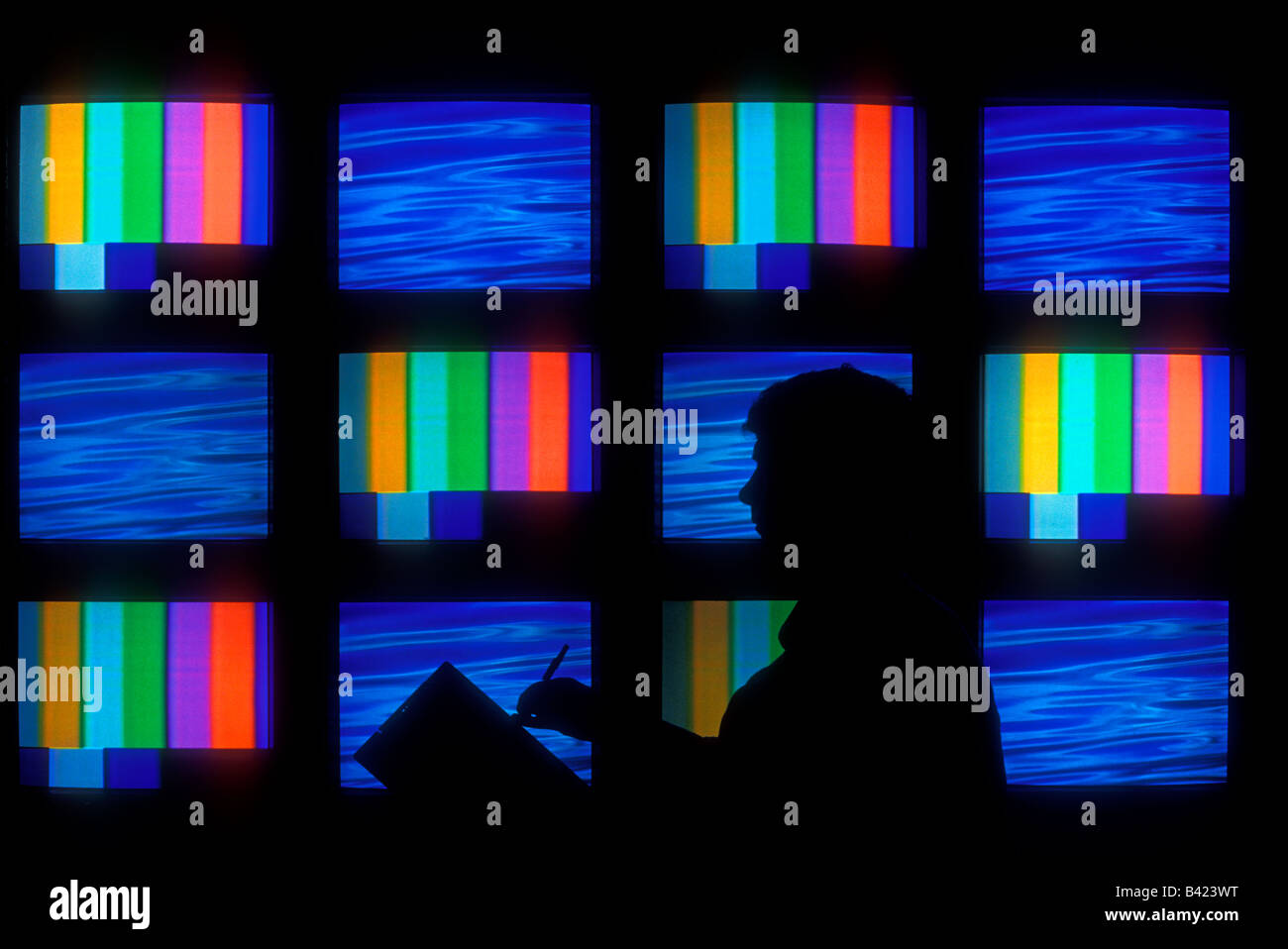 L'homme en face de moniteurs de télévision écrans vidéo Banque D'Images