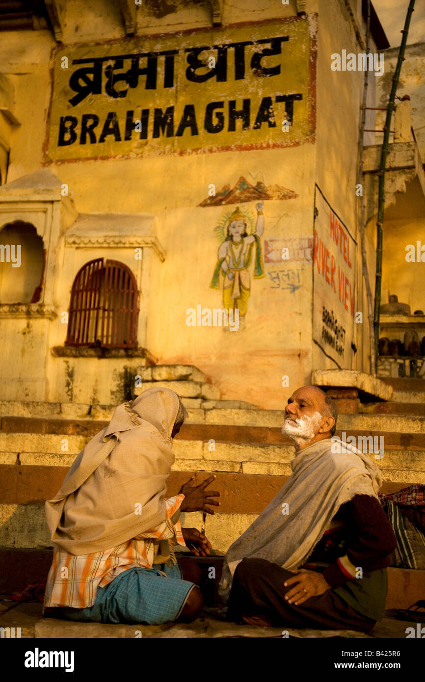 Un barbier rase un client sur les marches de la Brahma Ghat de Varanasi, Inde. Le client est libre couverte et prêt à être rasée. Banque D'Images