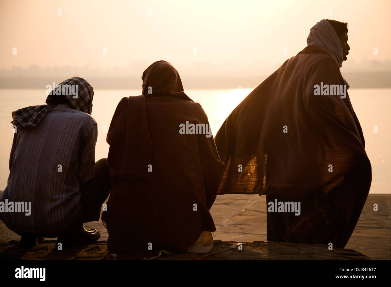 Trois hommes portent des capes et s'asseoir sur les rives du Gange le Gamnges à Varanasi, Inde. Banque D'Images