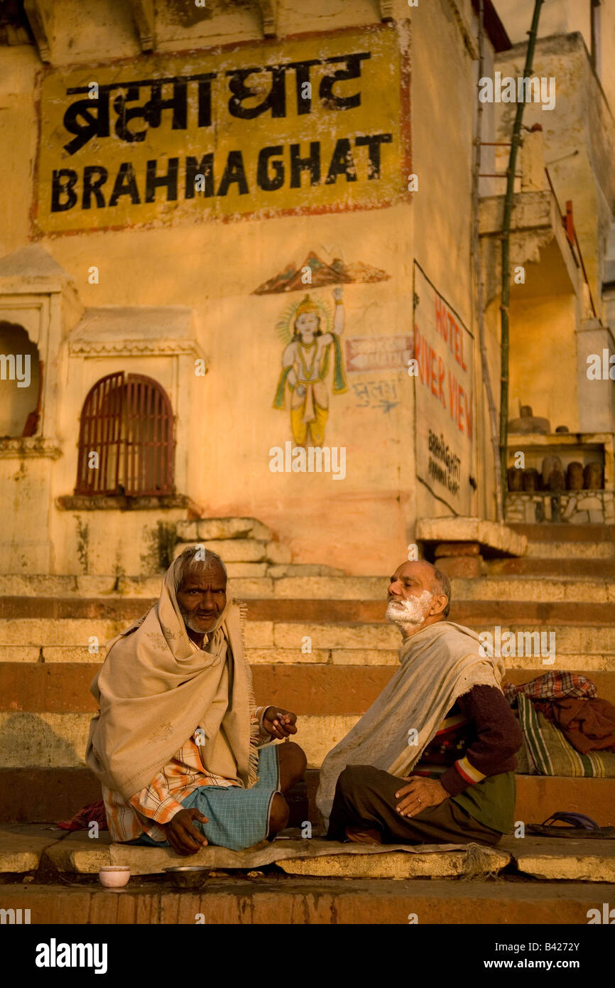 Un barbier rase un client sur les marches de l'Brahmaghat à Varanasi, Inde. Le client est libre couverte et prêt à être rasée. Banque D'Images