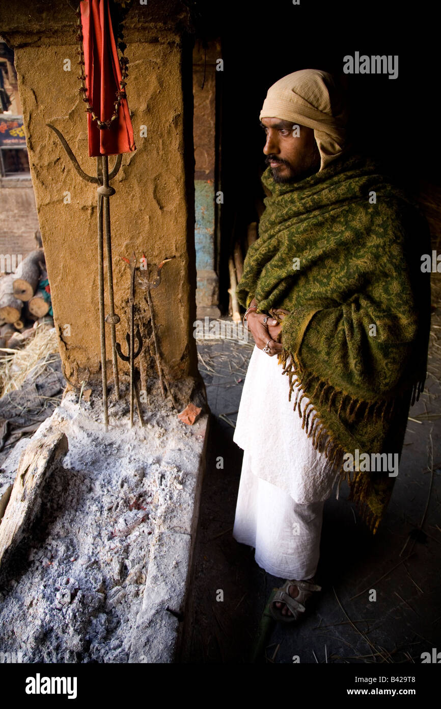 L'un des DOM, un intouchable qui dirige les cérémonies de crémation, maintient la flamme éternelle à l'aube dans la ville de Varanasi. Banque D'Images