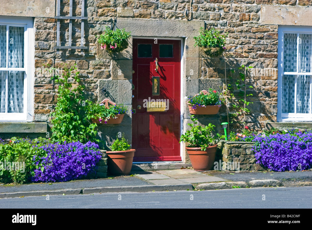 Porte avant rouge d'une maison traditionnelle en pierre dans village Blanchland North Pennines Grande-bretagne UK 2008 Banque D'Images