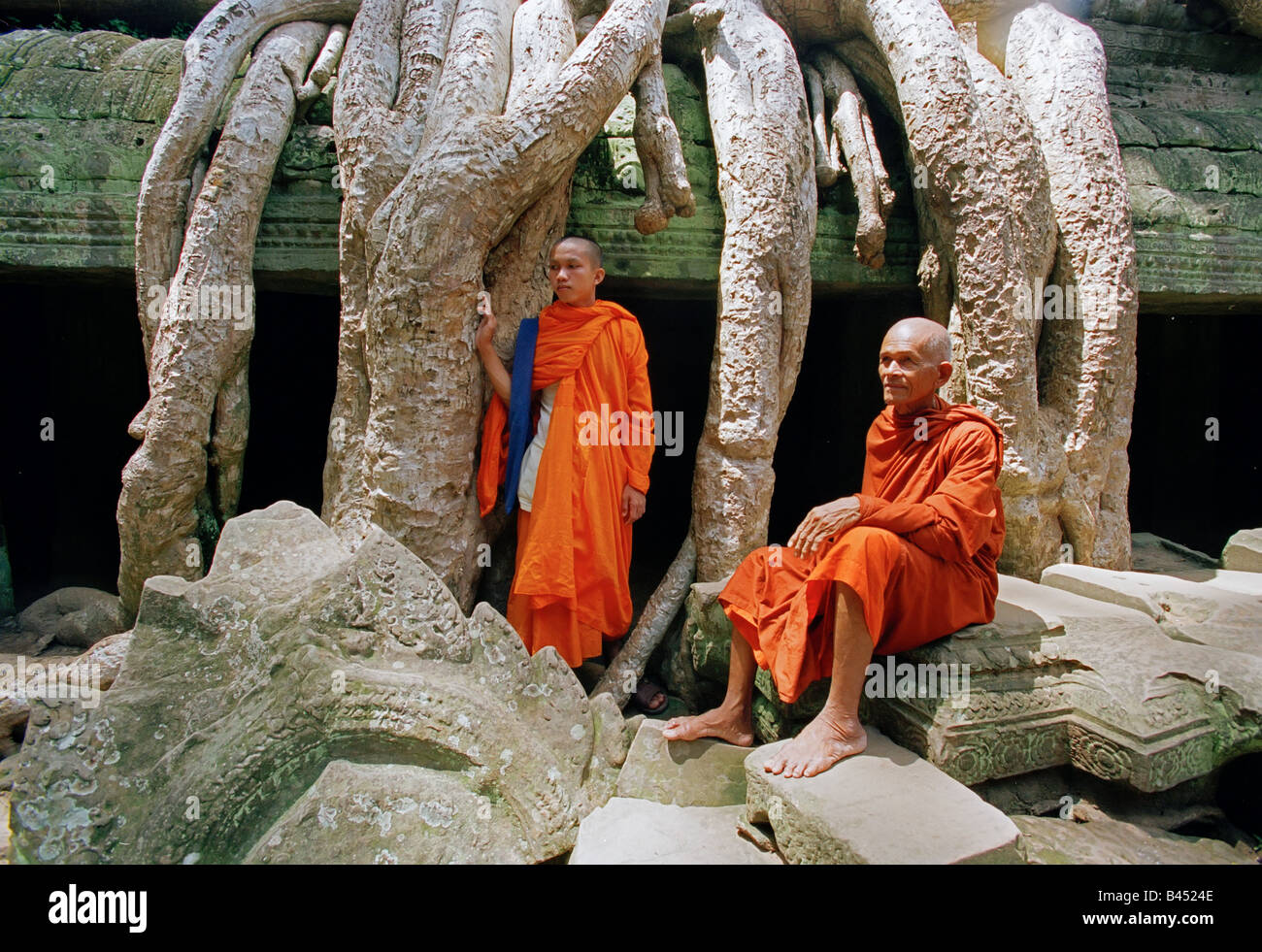 L'Asie, Cambodge, Siem Reap, Ta Prohm Temple, les moines debout parmi les racines du figuier géant Banque D'Images