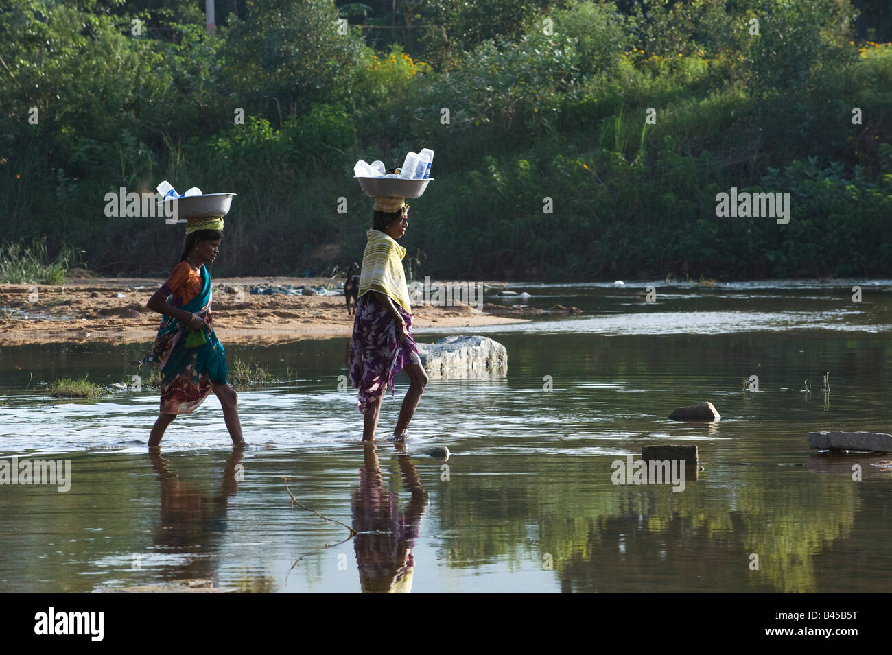 Village de l'Inde rurale des femmes par l'équilibrage de la rivière Chitravathi un bol en métal sur la tête. Puttaparthi, Andhra Pradesh, Inde Banque D'Images