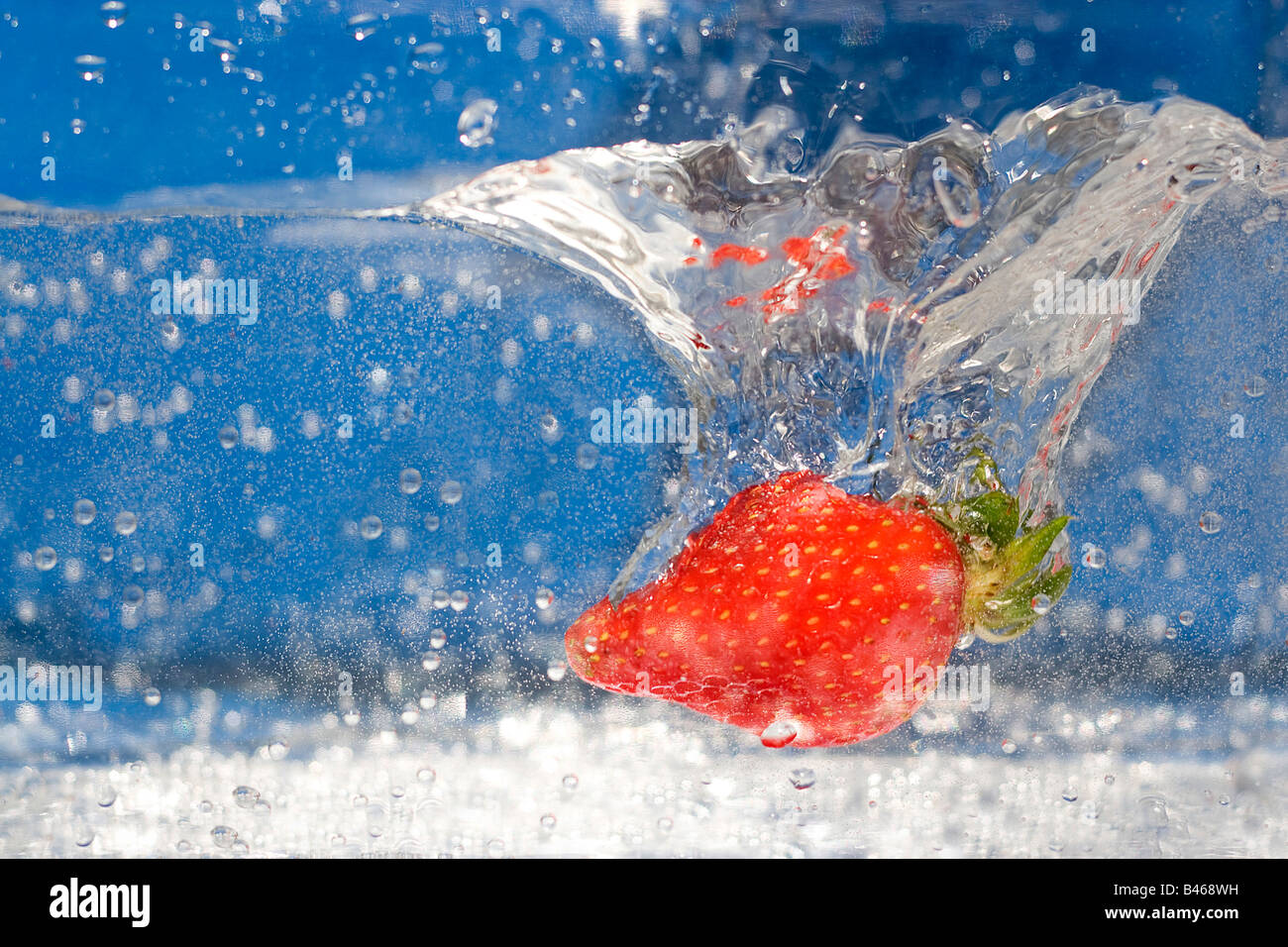 Une fraise rouge juteuse plongeant dans de l'eau Banque D'Images