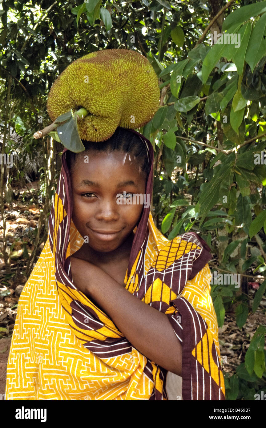 Une jeune fille porte un jack fruits, Artocarpus heterophyllus, le plus grand de tous les fruits des arbres, Zanzibar, Tanzanie Banque D'Images