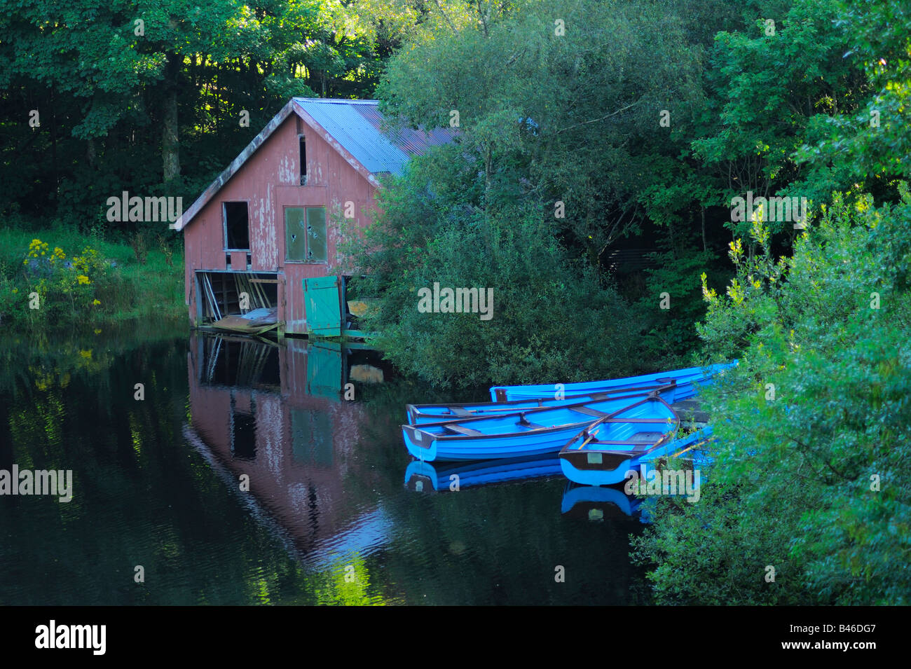 Photographie de l'atmosphère d'un vieux hangar à bateaux en bois et les barques de réfléchir sur un petit lac à côté de Lake Vyrnwy au Pays de Galles Banque D'Images