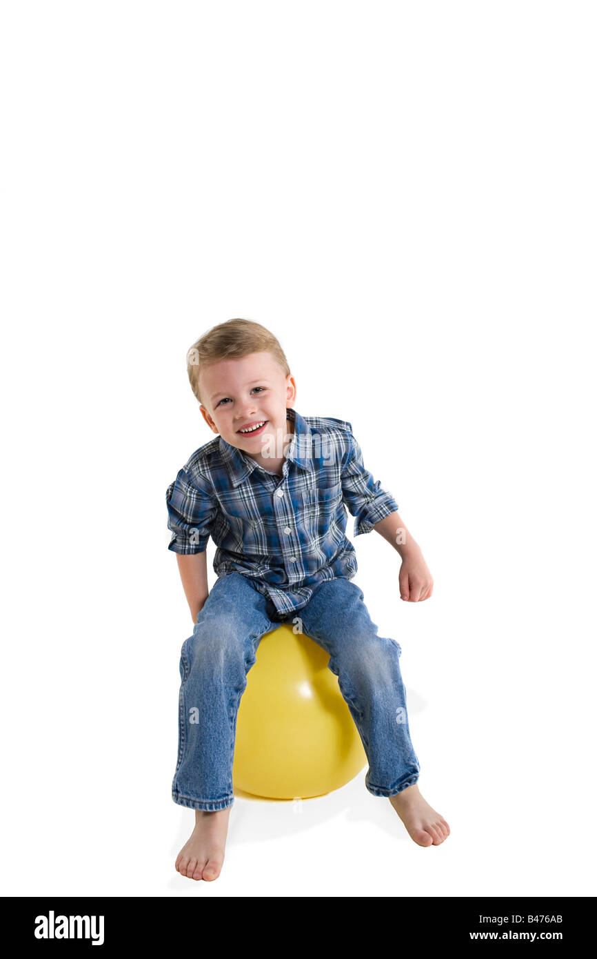 Un garçon assis sur une boule Banque D'Images
