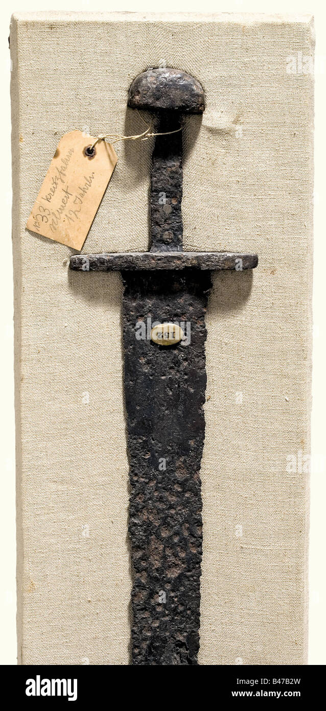 Une épée avec pommeau en forme de champignon, allemand, 2ème moitié du XIe siècle lame à double tranchant avec de légers fullers. Quillons arrondis sur les côtés. Pommeau de fer en forme de champignon avec un tenon cassé (soutenu et riveté). Conservée sur toute sa longueur, cette découverte d'excavation nettoyée montre des signes de corrosion importante. Longueur 87,5 cm. Monté dans le passé sur une plaque recouverte de lin avec une ancienne étiquette de collection. Longueur de la plaque 94,5 cm. Historique, historique, XIe siècle, épée, épées, armes, armes, armes, bras, dispositif de combat, militaire, militaria, objet, objets, s, Banque D'Images