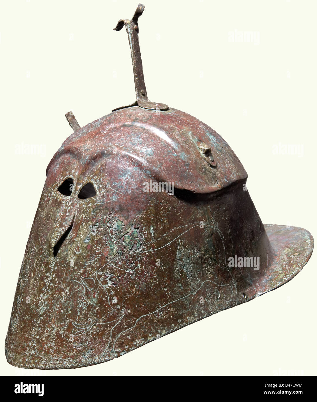 Un casque en bronze de type Apulian-Corinthian, dans le sud de l'Italie, la première moitié du 5ème siècle avant J.-C. Forgé en un morceau de bronze de feuille, la moitié supérieure séparée et fait légèrement plus large que les côtés par une crête extrudée. En haut, une fourche en bronze et les restes de deux supports latéraux, le front avec deux rangées de crêtes très hautes voûtées fixées sur des fentes d'yeux extrêmement petites en forme d'amande au-dessous desquelles un petit et légèrement proéminent 'nez'. Les joues gravées d'un grand et très gracieux, bien dessiné boar de chaque côté, les environs des yeux, du nez et de l'hel, Banque D'Images